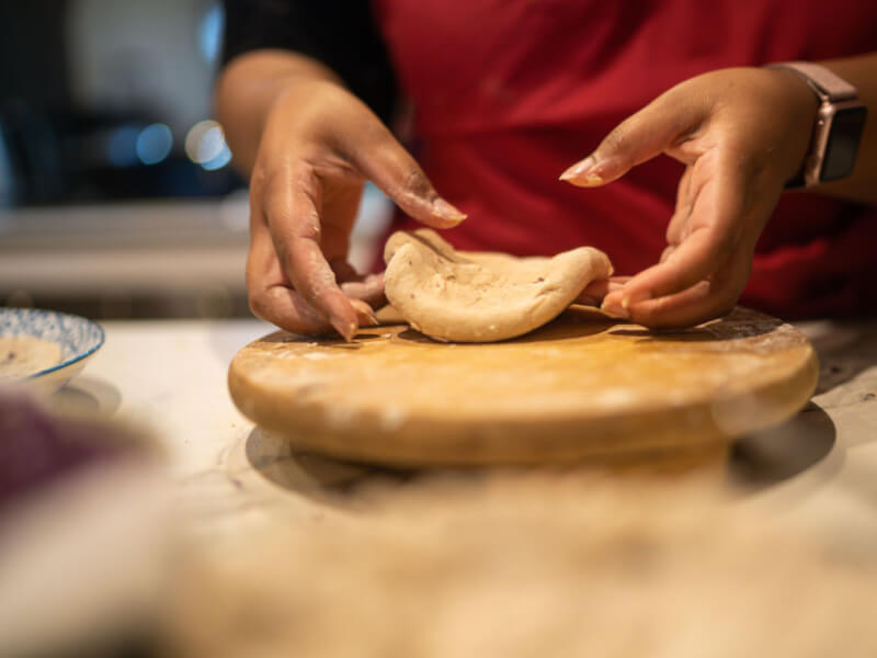 A woman kneads bread on a board 